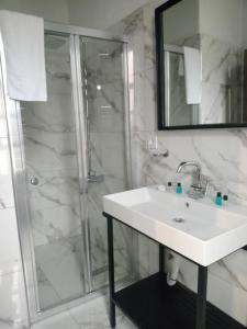 uma casa de banho branca com um lavatório e um chuveiro em Scala Otel em Cesme
