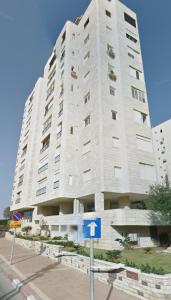 a large white building on the side of a street at Beach house in Netanya