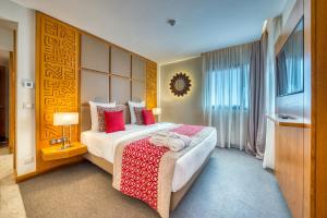 Cette chambre comprend un grand lit avec des oreillers rouges. dans l'établissement Azalaï Hôtel Dakar, à Dakar