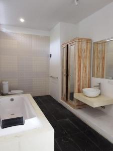 a white bathroom with a tub and a sink at Deepblue vila in Pulukan