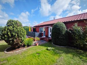 een klein rood huis met een tuin en struiken bij Ferienwohnung Hidde in Ostseebad Koserow