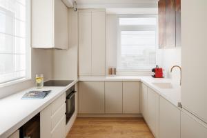 a white kitchen with white cabinets and a window at Skylark Central Aparthotel in Braşov