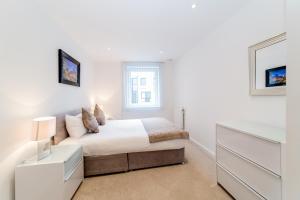 a white bedroom with a bed and a window at StayInn Greenwich in London