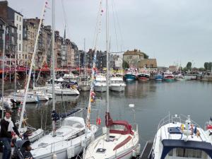 a group of boats docked in a harbor with buildings at L'Ex-Voto in Honfleur