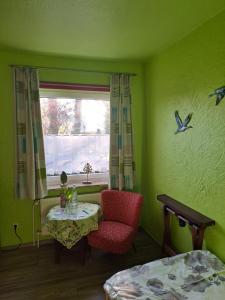 ビスピンゲンにあるPension Sanderのテーブルと椅子、窓が備わる客室です。