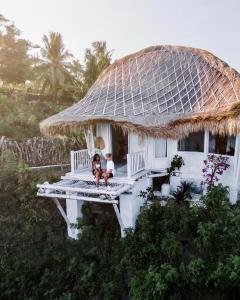 2 personnes assises sur une terrasse couverte d'une maison dans l'établissement Tropical Glamping Nusa Penida Diamond Beach - Cliff Side Edge, à Nusa Penida