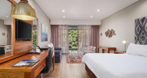 1 dormitorio con 1 cama y escritorio con TV en ANEW Resort Hunters Rest Rustenburg en Rustenburg