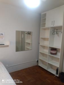 1 dormitorio con estantes blancos y espejo en Aconchego do Lar Centro BH Apto 633 Rua da Bahia 187 en Belo Horizonte