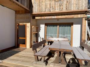 einen Holztisch und Bänke auf einer Terrasse in der Unterkunft IL Nido in Sappada