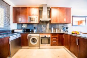 a kitchen with wooden cabinets and a washer and dryer at Malibu A1 · Luxury 2BR Panoramic Sea View Ref 242 in Fuengirola