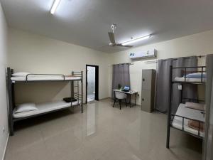 a room with three bunk beds and a desk at Viva Hostel Group Muscat in Muscat