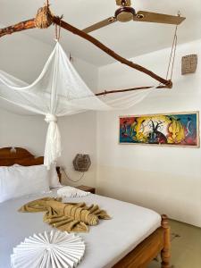 - une chambre avec un lit et un ventilateur de plafond dans l'établissement Mlango Paje House II, à Paje