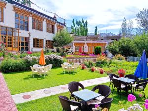 einen Garten mit Tischen und Stühlen und ein Gebäude in der Unterkunft Kidar in Leh