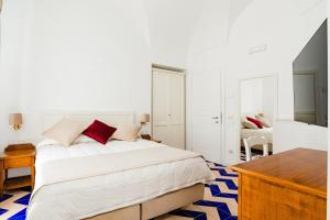 a white bedroom with a bed and a desk at Hotel Da Raffaele in Ischia