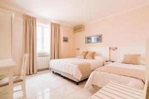 a hotel room with two beds and a desk at Hotel Da Raffaele in Ischia