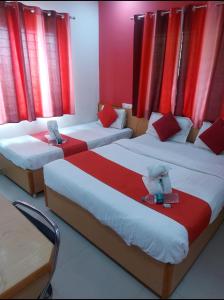 3 Betten in einem Zimmer mit roten Vorhängen in der Unterkunft Hotel City Plaza in Bangalore