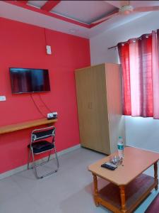 a room with a red wall with a table and a chair at Hotel City Plaza in Bangalore