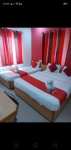 three beds in a room with red curtains at Hotel City Plaza in Bangalore