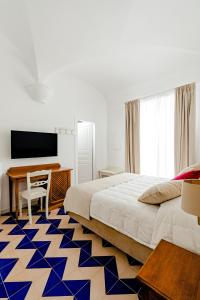 a bedroom with a bed and a desk and a television at Hotel Da Raffaele in Ischia