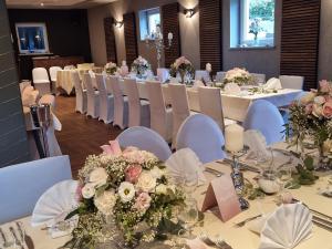 Hotel & Restaurant 4 Winden في فيندهاغن: مجموعة من الطاولات مع الكراسي البيضاء والزهور