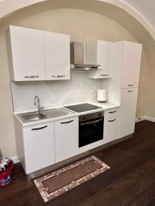 uma cozinha com armários brancos e um lavatório em Maison Petit Bonbon em Turim