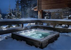a hot tub in the snow in front of a cabin at Chalets Jasná Collection Centrum in Belá