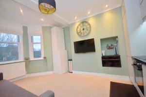 a living room with a clock on the wall at 2 Bedroom Flat London,Sleeps 6, Top Floor, Roof Terrace, Next to Brixton Underground Station in London