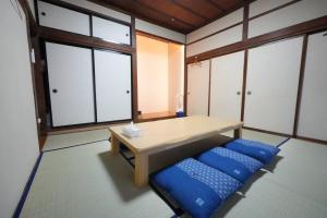 een kamer met een houten tafel en blauwe kussens bij シアタールーム付き！駅徒歩7分の好立地！【藍Restvillage松本】 in Matsumoto