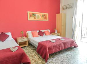 1 dormitorio con 2 camas y paredes de color rojo en Actinia Accommodation, en Alghero
