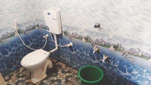 a bathroom with a toilet with a mural on the wall at Candle wood Beach Stay in Gokarn