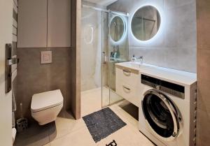a bathroom with a washing machine and a shower at Planty Park Apartament in Nowy Sącz