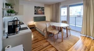 Habitación pequeña con cama, mesa y cocina en Planty Park Apartament en Nowy Sącz