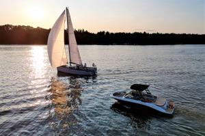 two boats in the water with a sail boat at Slow River Apartment in Nowe Miasto Lubawskie