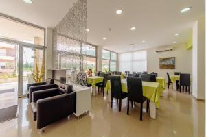ein Esszimmer mit gelben Tischen und schwarzen Stühlen in der Unterkunft Hotel Novi in Herceg-Novi