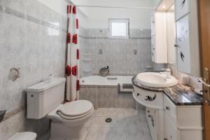 a bathroom with a toilet and a sink and a tub at Casa Garden in Archangelos +11 photos