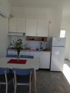a kitchen with a white refrigerator and a table with chairs at Cozy Rodas House 1 in Skála