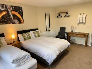 a bedroom with two beds and a desk and a chair at Forces Manor in Kincraig