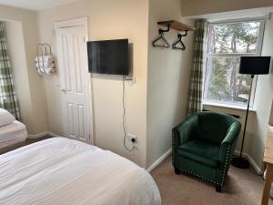 a bedroom with a bed and a green chair at Forces Manor in Kincraig