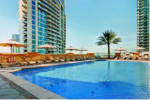 a large swimming pool with chairs and umbrellas at HOMESTAR, Jumeirah Beach Hostel - JBR - Pool, Beach, Metro in Dubai