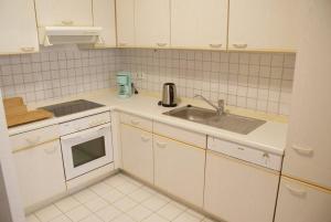 una cocina con armarios blancos y fregadero en Altstadtleben - ABC164 en Wismar