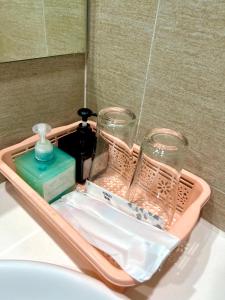a basket with a bottle of soap and glasses on a sink at Mayhomes 34m2 Vinhomes Grand Park in Long Bình