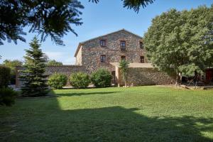 un grand bâtiment en pierre avec des arbres dans une cour dans l'établissement Rincón de piedra BCN, à Corró de Vall