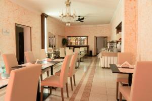 uma sala de jantar com paredes cor-de-rosa, mesas e cadeiras em Albergo San Lorenzo em Grosseto