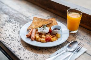 a plate of breakfast food with toast and a glass of orange juice at Kokotel Krabi Ao Nang in Ao Nang Beach