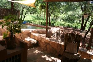 a patio with a stone wall next to a river at Kiburi Lodge @ Kruger, a secluded Bushveld getaway in Marloth Park