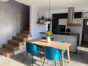 cocina y comedor con mesa de madera y sillas azules en Casa Matko, en Kostanjevica na Krasu