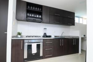 a kitchen with dark brown cabinets and a stove at Comodo y amplio apartamento en Valledupar cerca al Parque la Leyenda in Valledupar