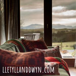 a living room with a couch and a large window at Tyddyn Plwm Isa in Newborough