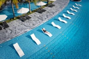 an overhead view of a swimming pool with white chairs and umbrellas at Mövenpick Resort Waverly Phu Quoc in Phu Quoc