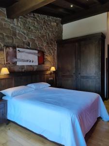 1 dormitorio con 1 cama grande en una pared de piedra en Casa Rural Ubales, 